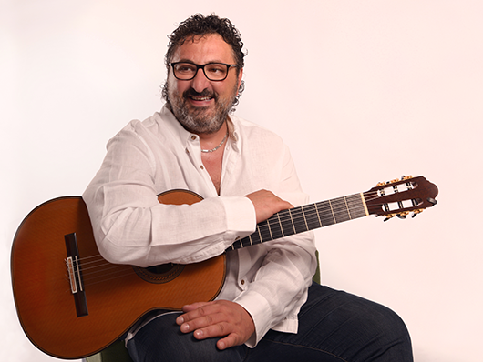 Aniello Desiderio smiling with his guitar