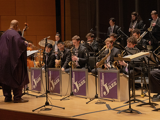 Jazz orchestra students perform seated onstage.