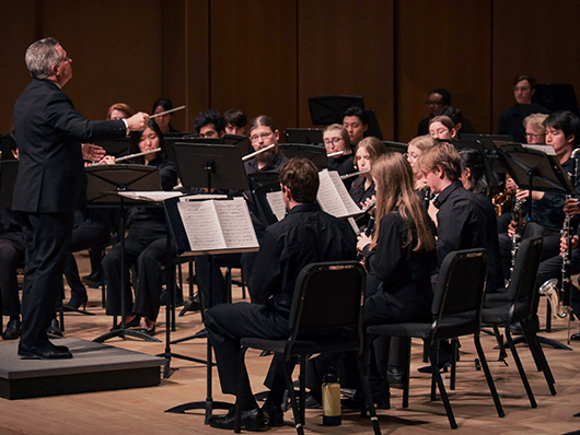 A conductor leads woodwinds players.