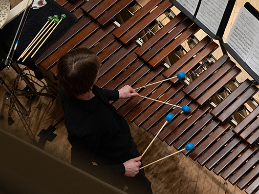 An overhead angle of a musician playing a marimba with two mallets in each hand.