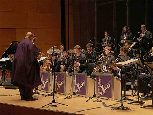 Derrick Gardner conducts the jazz orchestra onstage.