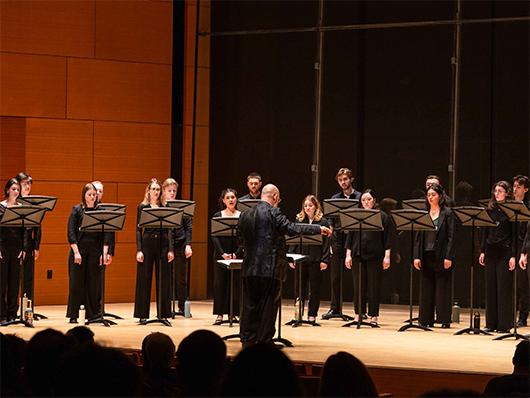 Andrew Megill conducts a choir onstage at Galvin Recital Hall.