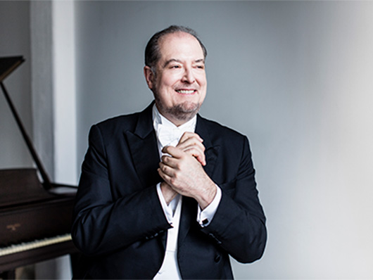 Garrick Ohlsson smiles in front of a piano.