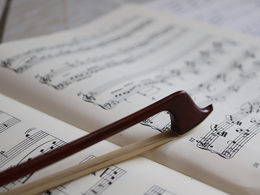 A bow sits on sheet music.