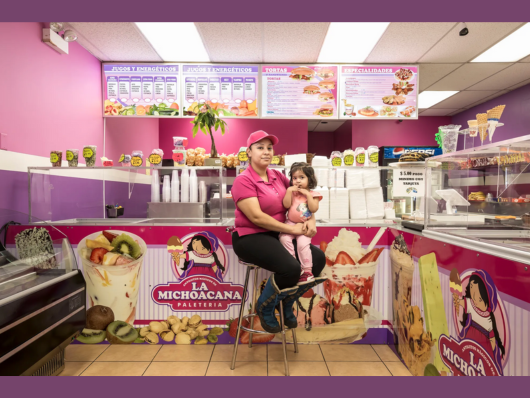 photograph of woman and child sitting inside of a pink and purple Mexican ice cream shop