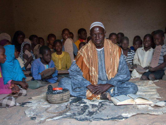 man sitting surrounded by children