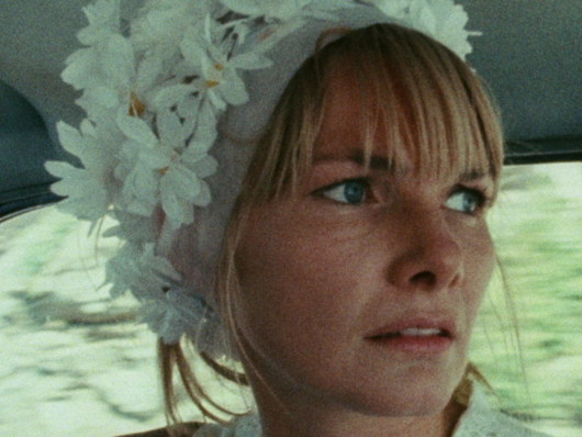 Blonde woman wearing a floral cap looks pensively