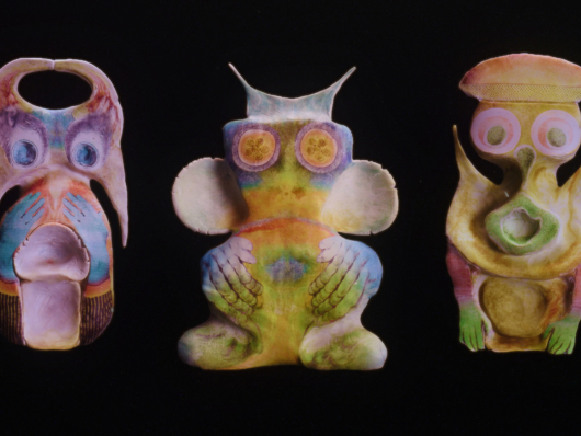 three colorful figurative sculptures on black background