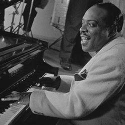Black and white photo of Count Basie playing the piano