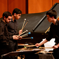 Percussionists performing on a well lit stage