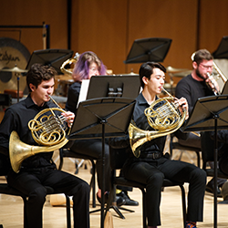 Brass players wearing black perform on stage.