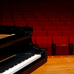 A grand piano in front of an empty theater