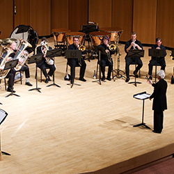 Brass musicians performing in a semicircle onstage