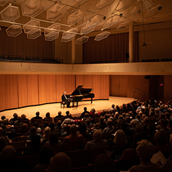 Jeffrey Siegel, seated at a grand piano, speaks to the audience in Pick-Staiger Concert Hall