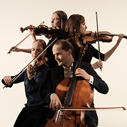 The members of the Dudok Quartet Amsterdam sit back to back, playing their instruments against a white backdrop