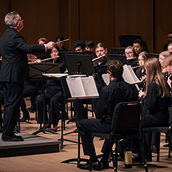 A conductor leads woodwinds players.