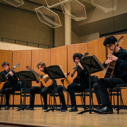 Four classical guitarists play seated.