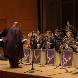 Derrick Gardner conducts the jazz orchestra onstage.