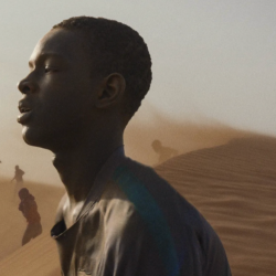 Profile view of a man staring to the left against a background of sand dunes