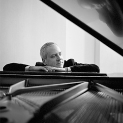 Jeremy Denk at the piano in black and white.