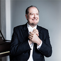 Garrick Ohlsson smiles in front of a piano.