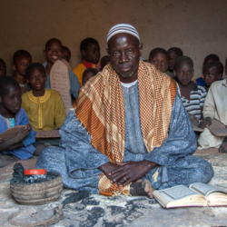 man sitting surrounded by children