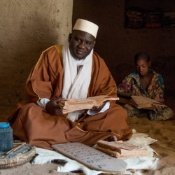 man sitting cross-legged with child sitting cross-legged behind him