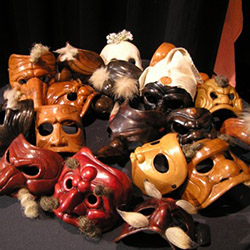 Artfully arranged masks on a table. The expressions of the masks are striking and exaggerated.
