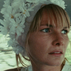 Blonde woman wearing a floral cap looks pensively