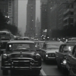 black and white film still of cars driving through downtown chicago