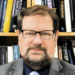 
								A headshot of Andreas Hielscher sitting in front of a full bookshelf.